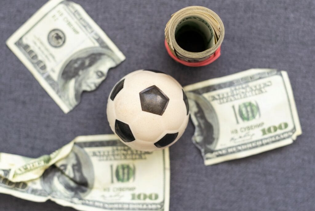 Toy soccer ball amid US currency indicative of Wisconsin Gov. Evers spending ARPA funds on building projects